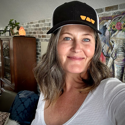 Smiling middle aged woman wearing a Schluter hat.