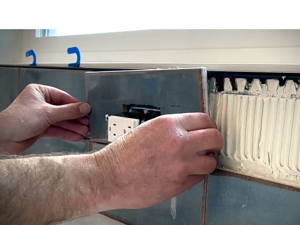 Tile installer sets a piece of tile on a Schluter edge profile.